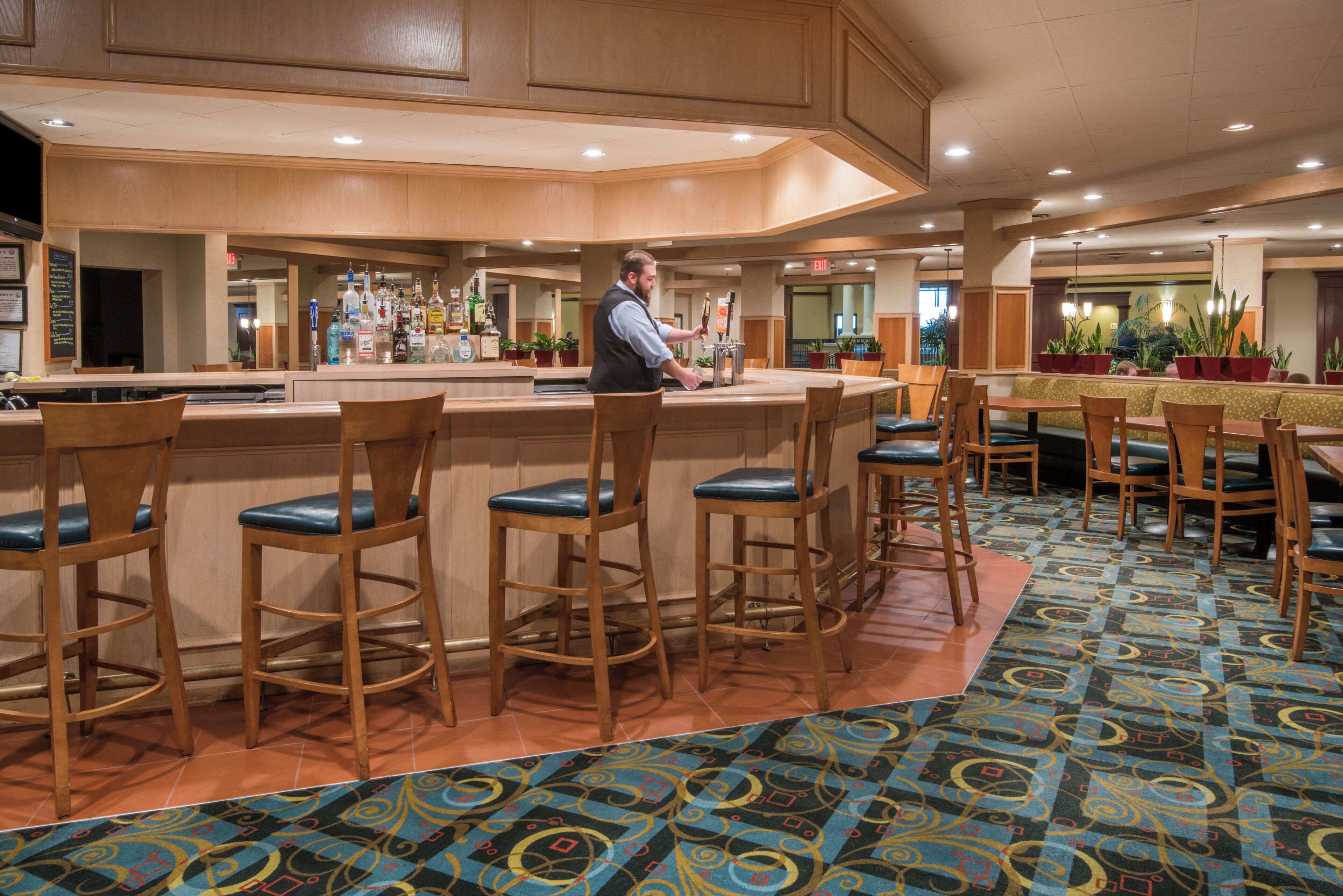 A bar area with wooden bar stools and a bartender.