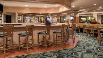 A bar area with wooden bar stools and a bartender.