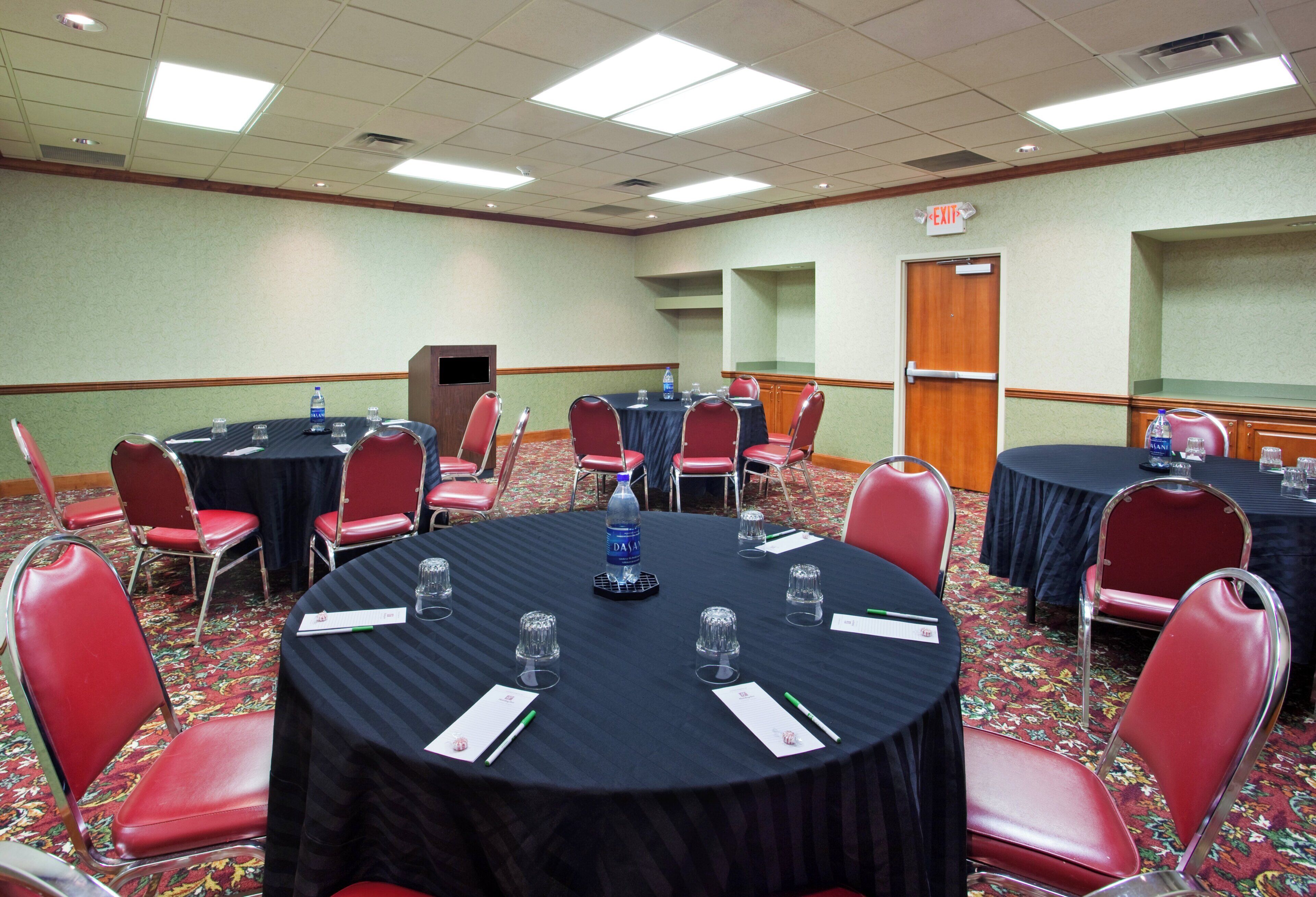A conference room with round tables, red chairs, and water bottles.