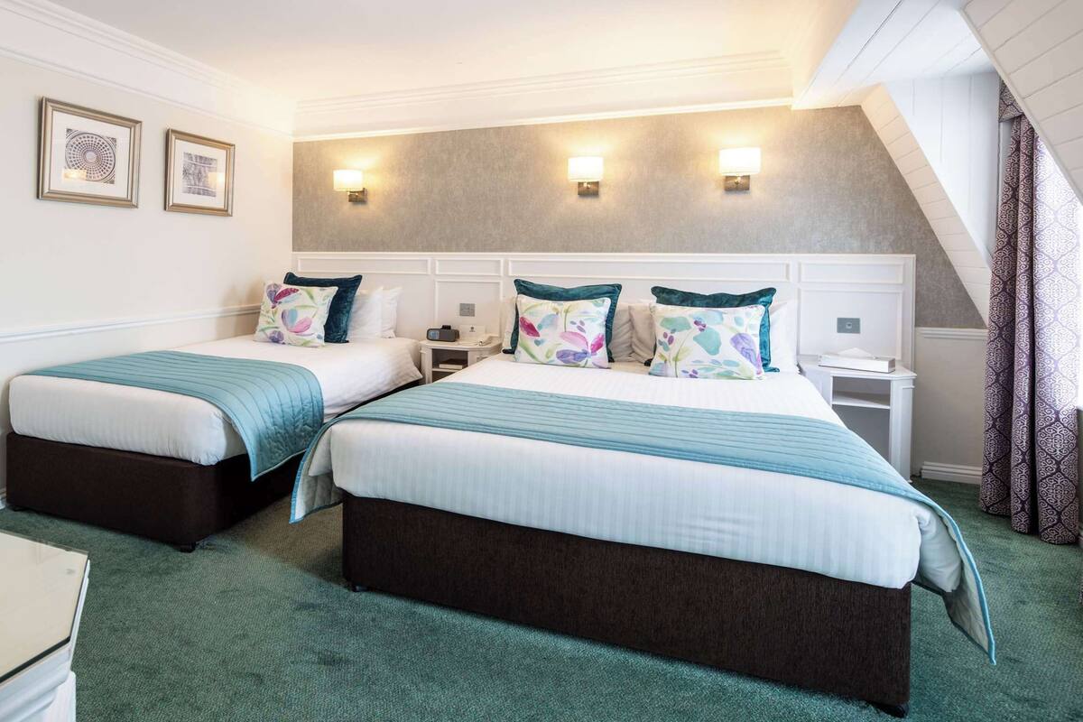 A hotel room with two beds, a desk, and a chair.