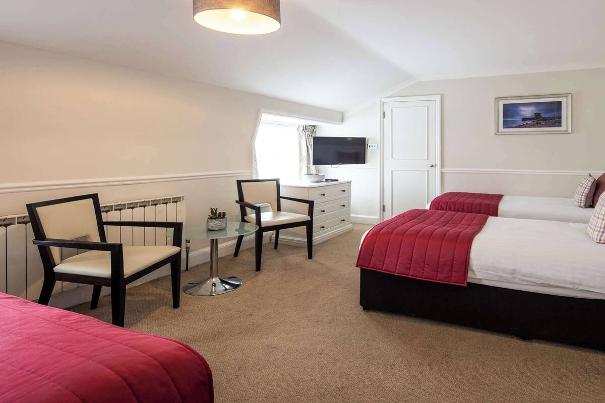 A bedroom with a bed, two chairs, a desk, and a television.