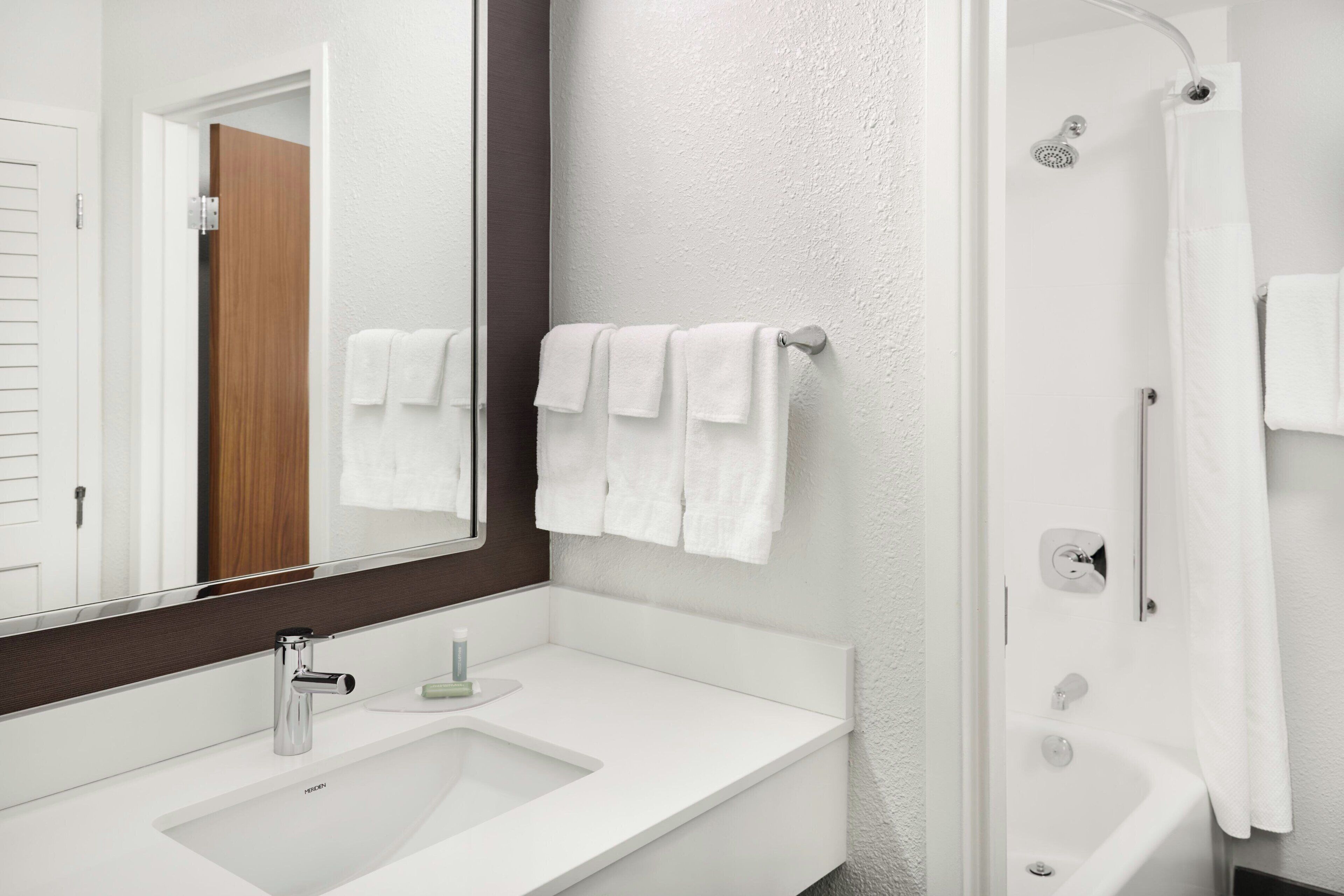 A bathroom with a white sink, a mirror, and a shower.