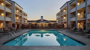 A swimming pool surrounded by a building with multiple balconies and lounge chairs. - Courtyard by Marriott Huntsville University Drive (Huntsville)