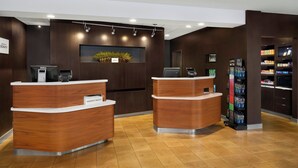 A reception area with two wooden reception desks, a digital kiosk, and a vending machine. - Courtyard by Marriott Huntsville University Drive (Huntsville)