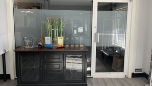 Un mostrador de recepción con premios, un florero con flores y una puerta de vidrio que da a un área de vestíbulo.