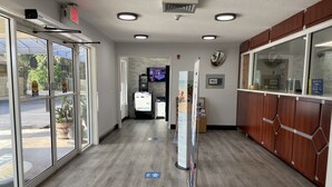 Un área de recepción con puerta de vidrio, mostrador de recepción y pantalla digital.