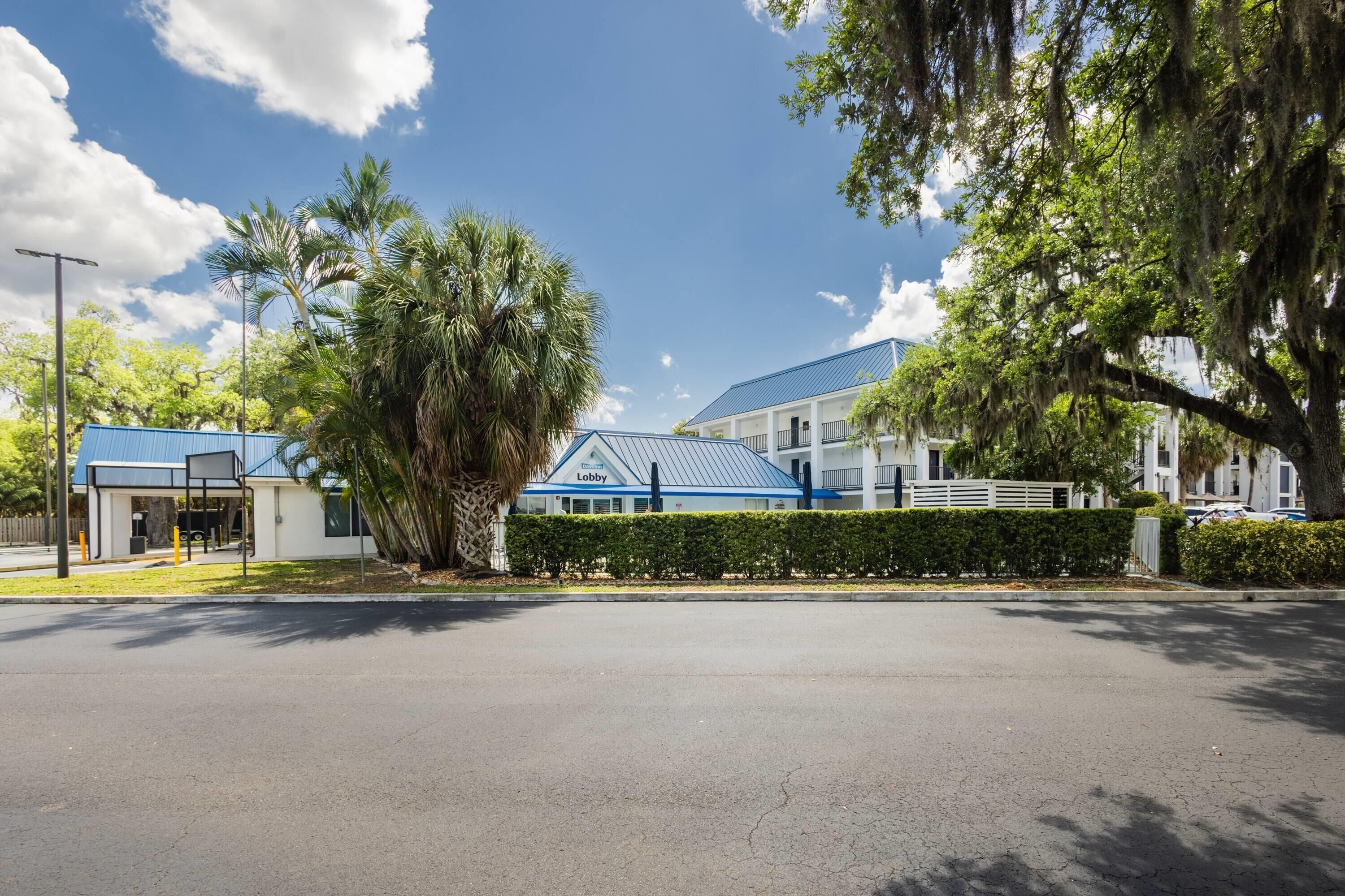 A building with a blue roof, a white facade, and a hedge in front.