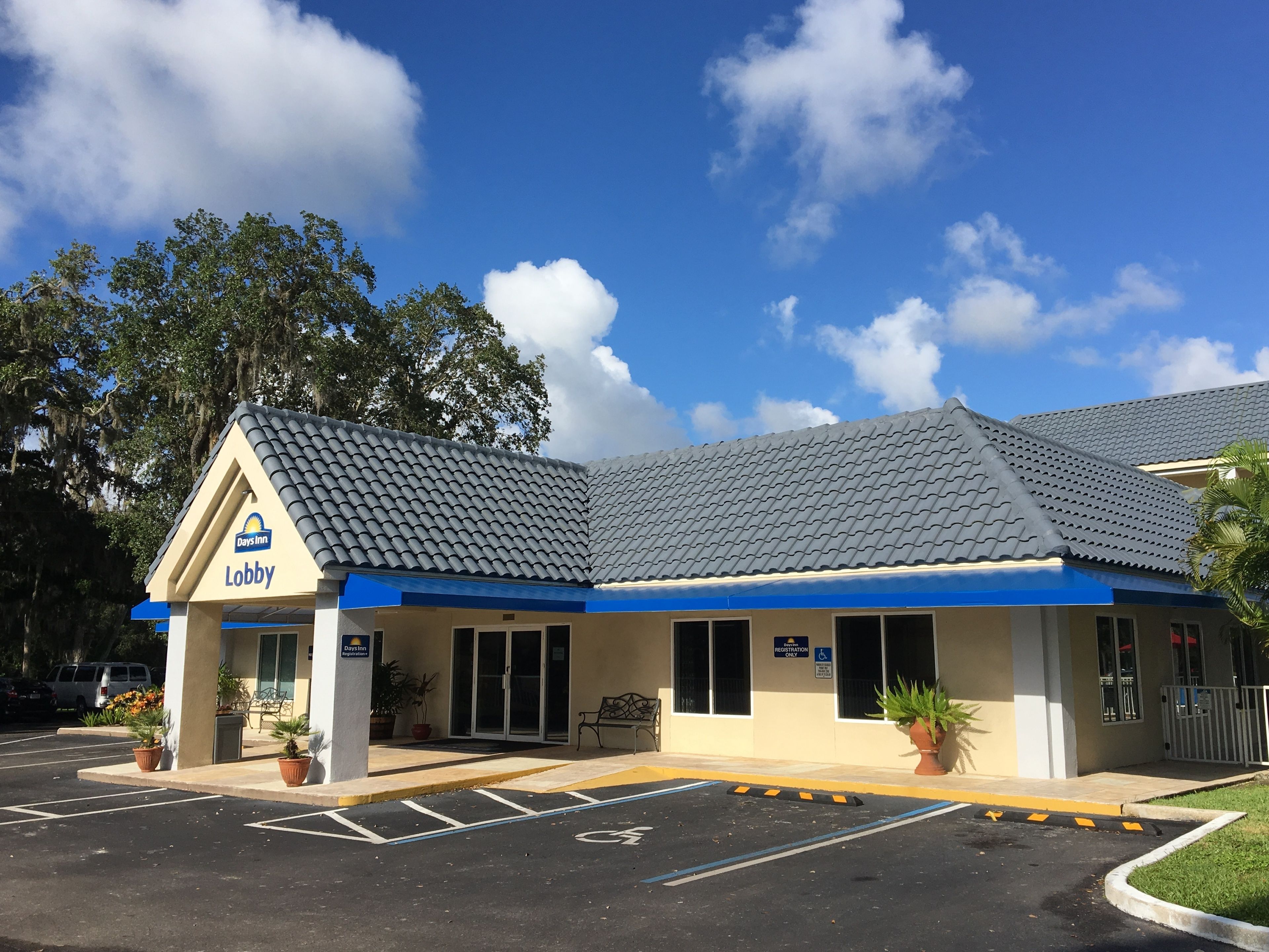 A Days Inn lobby with a tiled roof, a registration sign, and a handicapped parking space.