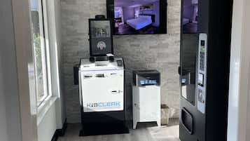 Et moderne hotelværelse med stenvæg, fjernsyn monteret på væggen, minibar og digital kiosk.