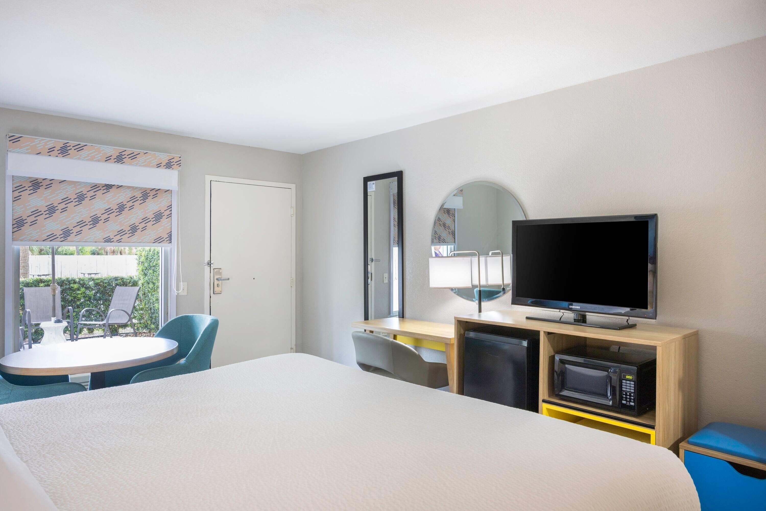 Une chambre d’hôtel comprenant un lit, un bureau avec une télévision, un four à micro-ondes et une chaise.