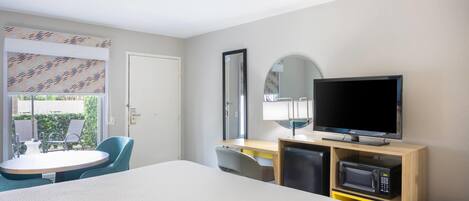 Une chambre d’hôtel comprenant un lit, un bureau avec une télévision, un four à micro-ondes et une chaise.