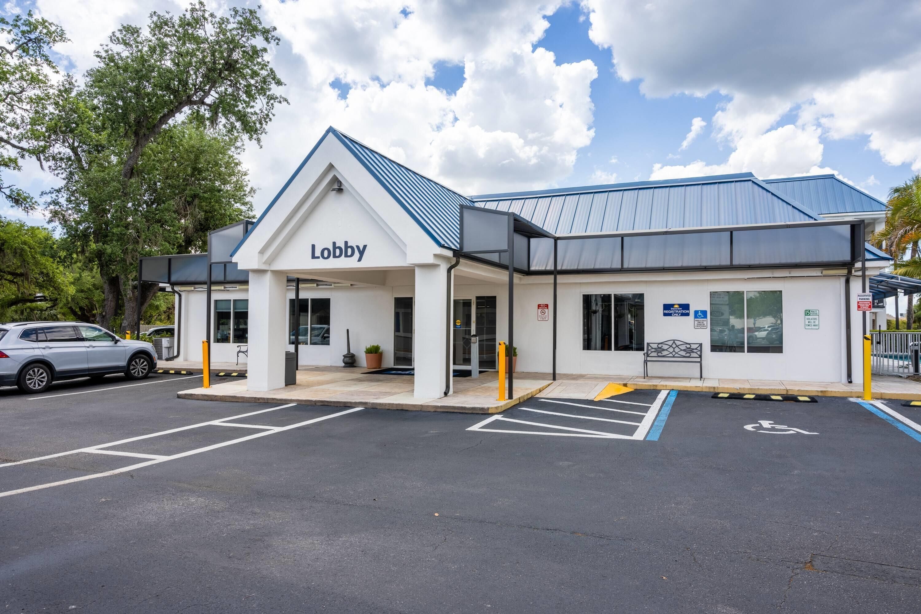 A building with a sign reading 'Lobby' at the entrance, a parking area with marked spaces, and a blue roof.