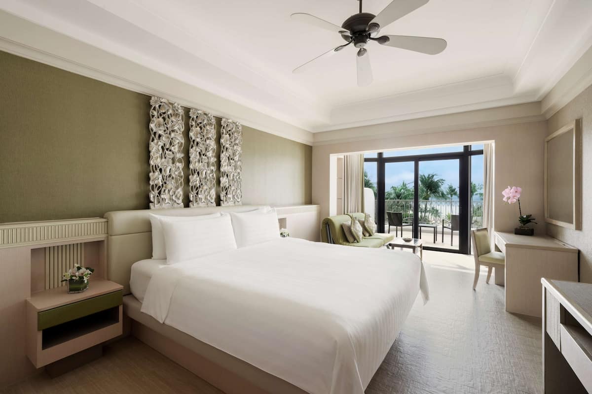 A spacious bedroom with a large bed, a ceiling fan, and a view of the outdoors.