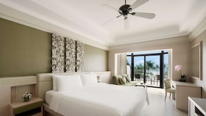 A spacious bedroom with a large bed, a ceiling fan, and a view of the outdoors.