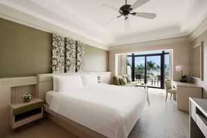 A spacious bedroom with a large bed, a ceiling fan, and a view of the outdoors.