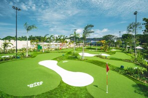 A well-maintained golf course with a clear path, palm trees, and a flag on the green.