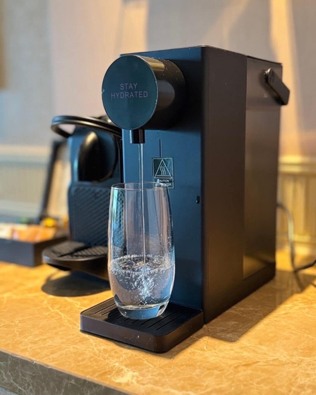 A water dispenser with a glass on a countertop.
