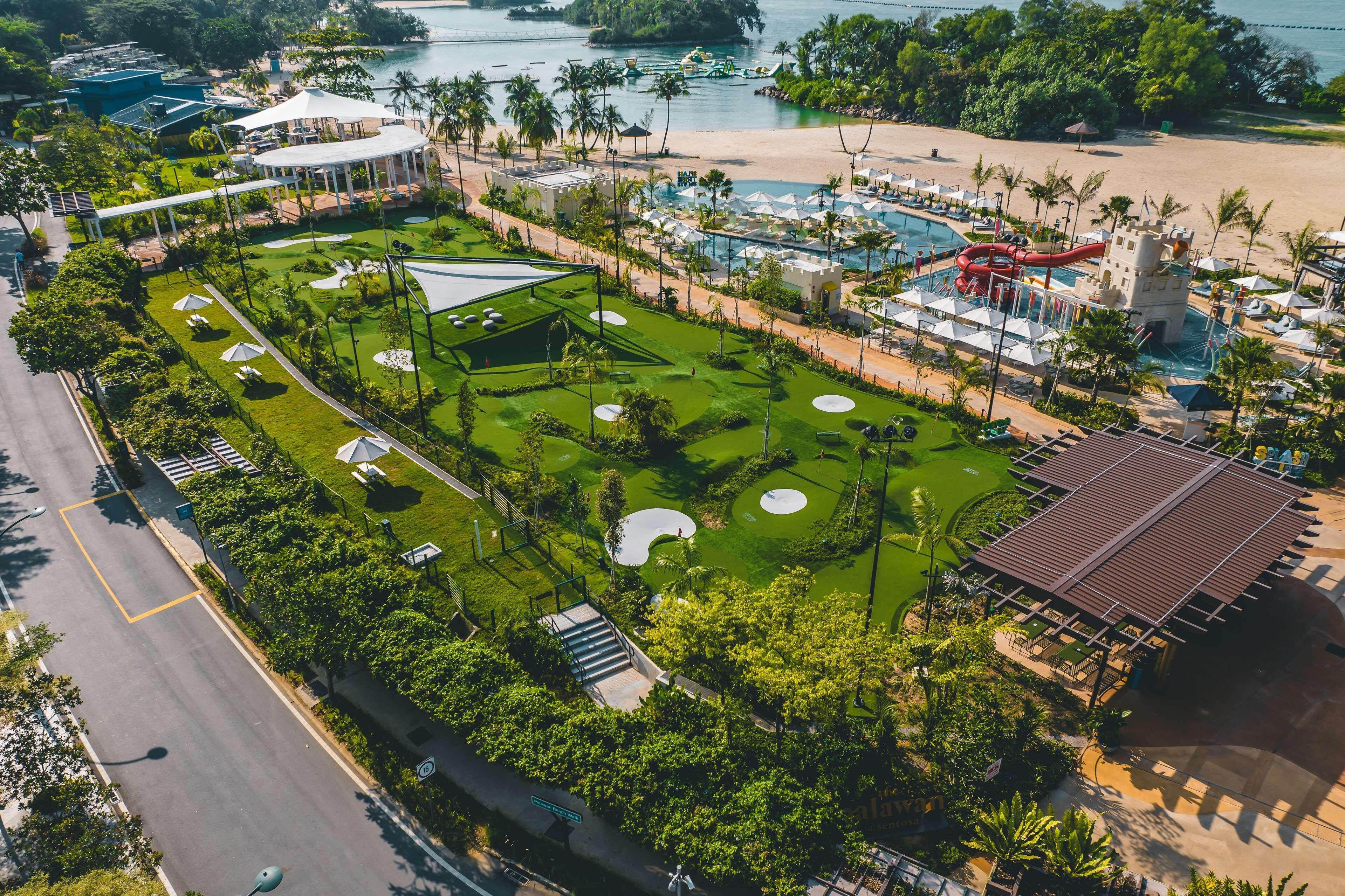 An aerial view of a resort with a swimming pool, beach, and a castle-like structure.