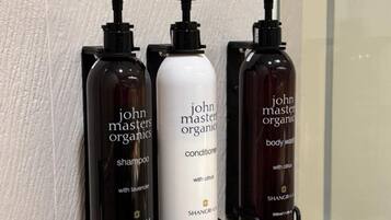 Tres botellas de productos John Masters Organics sobre una encimera de baño.