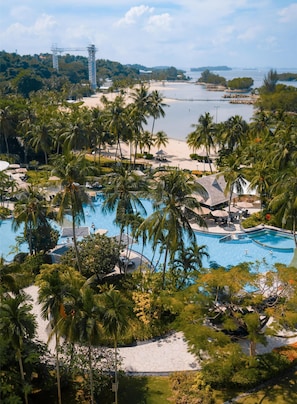 A resort with a large swimming pool surrounded by palm trees and a beach. - Shangri-La Rasa Sentosa, Singapore (Singapore)