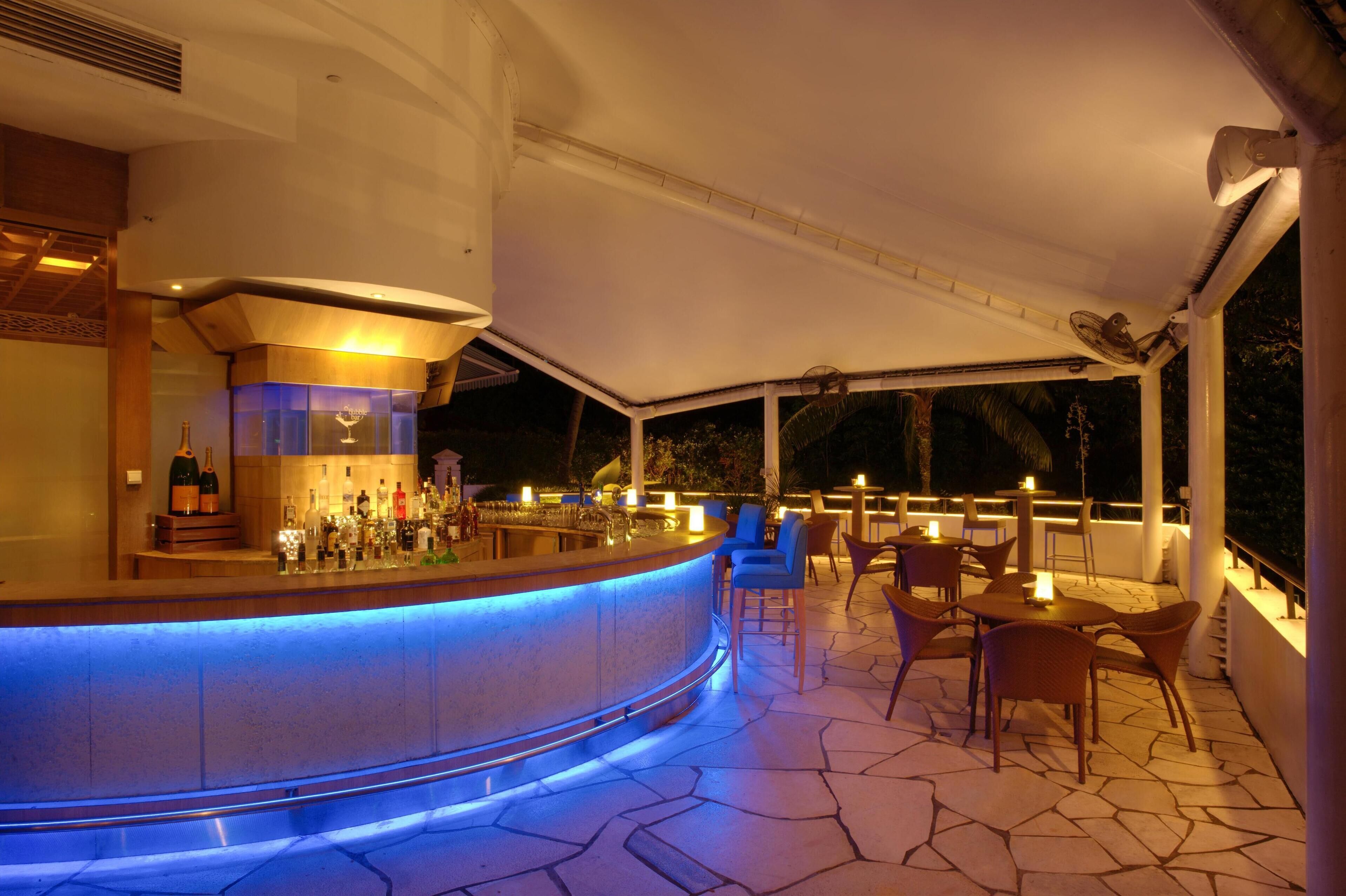 A bar area with a curved counter, seating, and a view of the outdoors.