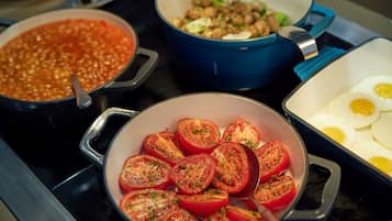 Un plan de travail de cuisine sur lequel on trouve différents plats, notamment un pot de soupe, un plat de tomates en tranches et un plat d’œufs.
