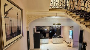 A hotel lobby with marble reception desks, a chandelier, and a staircase with ornate ironwork. - Thistle London Holborn (London)