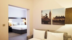 A hotel room with a bed, a sofa, and two wall-mounted pictures of a cityscape. - Thistle London Holborn (London)