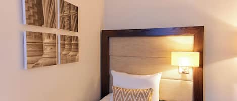 A neatly made bed with a wooden headboard, a bedside lamp, and a telephone on a nightstand.