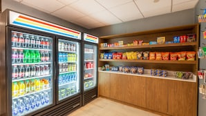A snack and beverage vending area with multiple refrigerated drink dispensers and shelves stocked with various snacks and chips. - Holiday Inn Express Philadelphia NE - Bensalem by IHG (Bensalem)