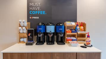 En kaffestation med flera kaffedispensrar, en skylt med texten ”KAFFE ÄR ETT MÅSTE” och diverse produkter relaterade till kaffe.