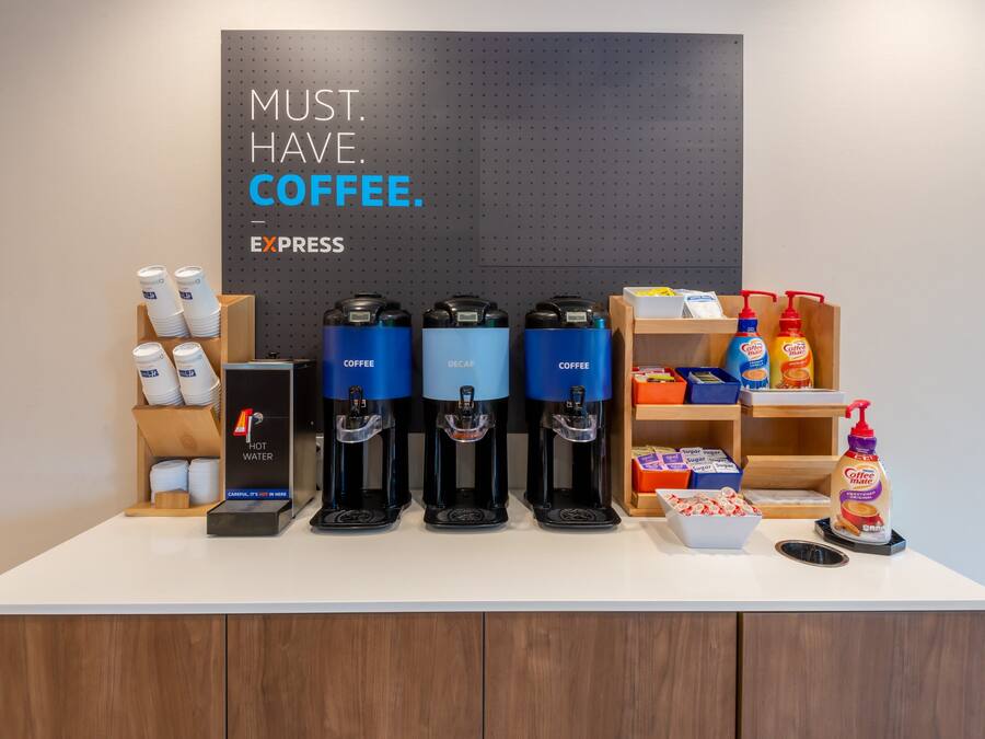 En kaffestation med flera kaffedispensrar, en skylt med texten ”KAFFE ÄR ETT MÅSTE” och diverse produkter relaterade till kaffe.