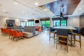 A modern cafe with a variety of seating options including tables, chairs, and a sofa area. - Holiday Inn Express Philadelphia NE - Bensalem by IHG (Bensalem)