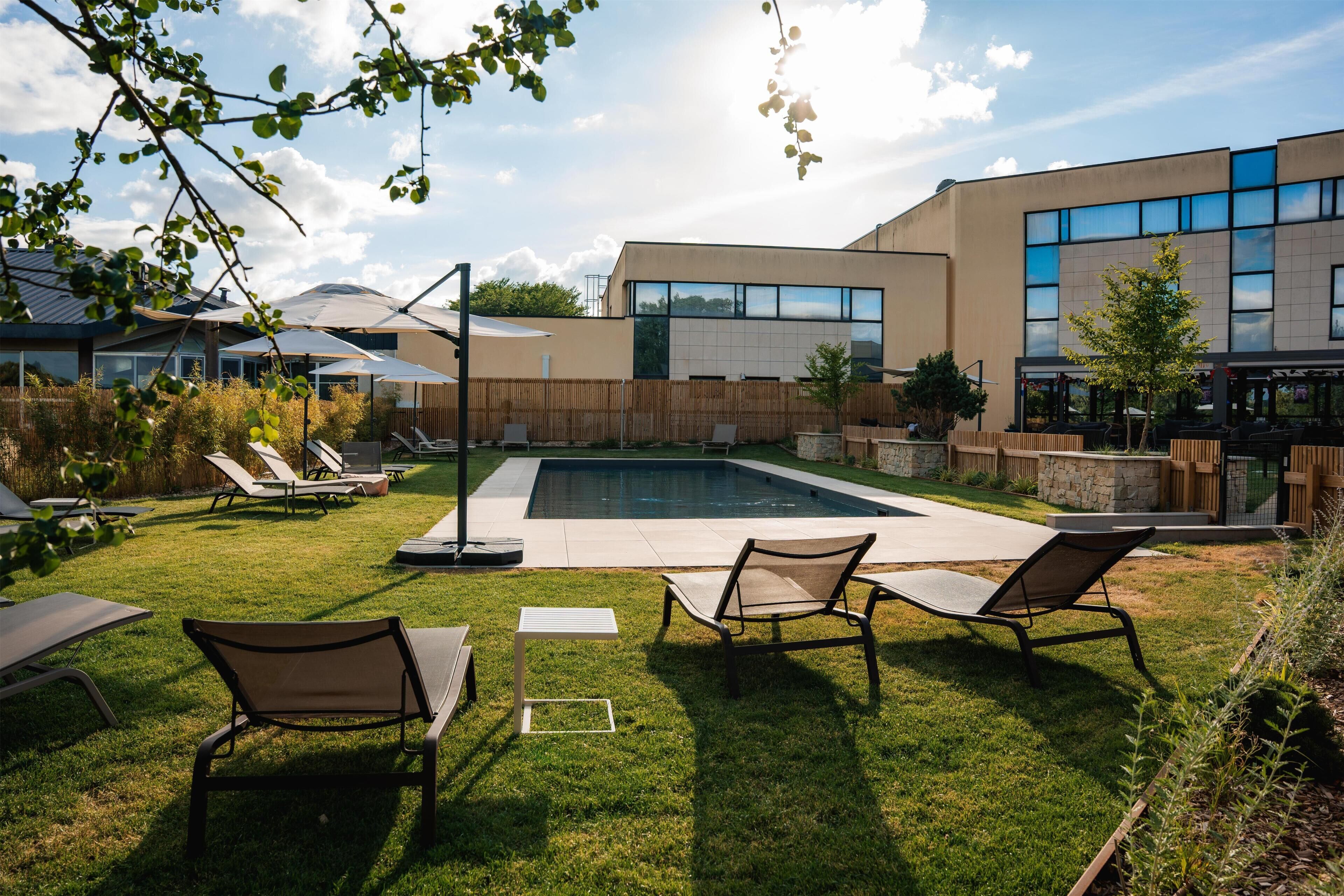 Un espace piscine extérieur moderne, doté de chaises longues et d’une clôture en bois.