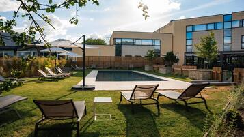 Un área de piscina moderna al aire libre con sillones de descanso y una cerca de madera.