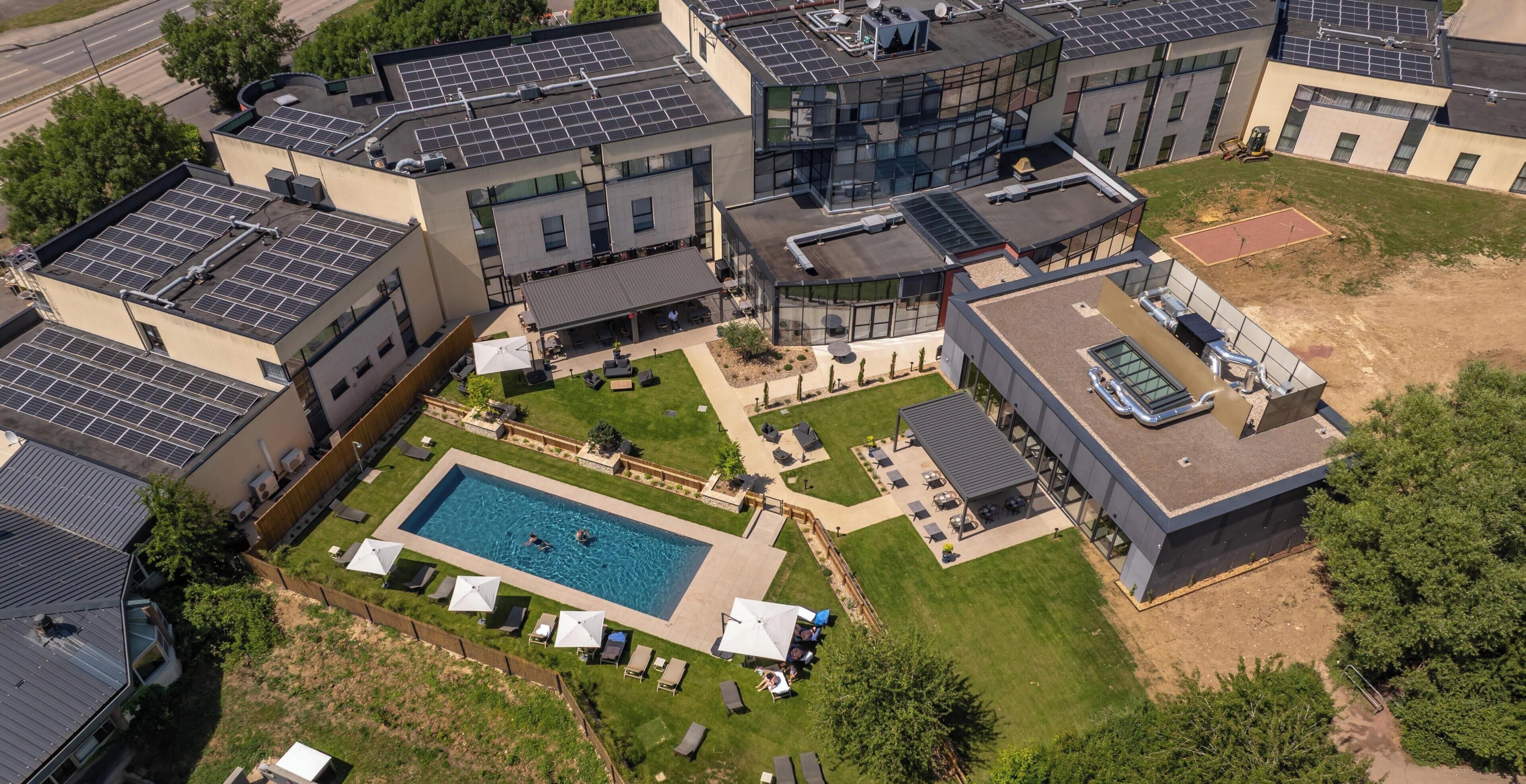 A modern building with multiple floors, a rooftop pool, and solar panels.