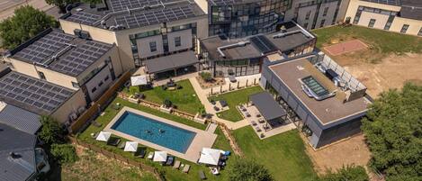 A modern building with multiple floors, a rooftop pool, and solar panels.