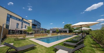 Una piscina al aire libre de temporada, sillones reclinables de piscina