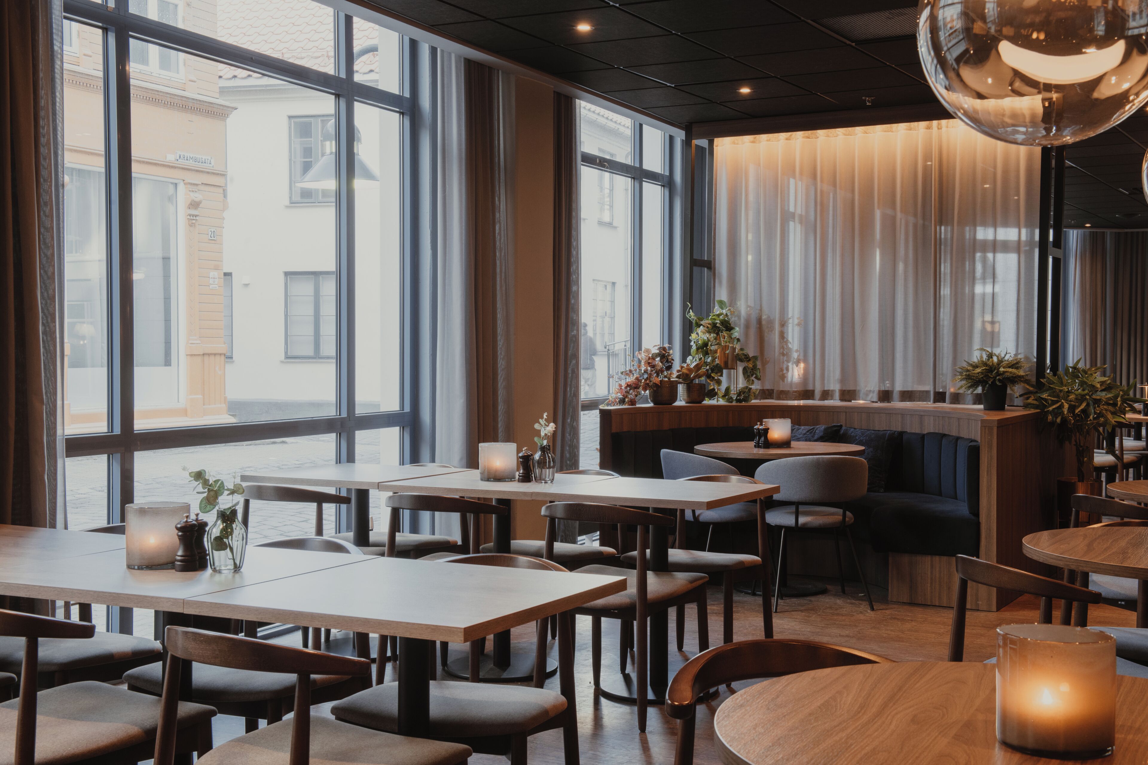A restaurant with large windows, wooden tables, and chairs.