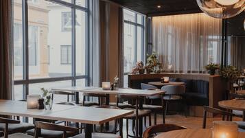 A restaurant with large windows, wooden tables, and chairs.