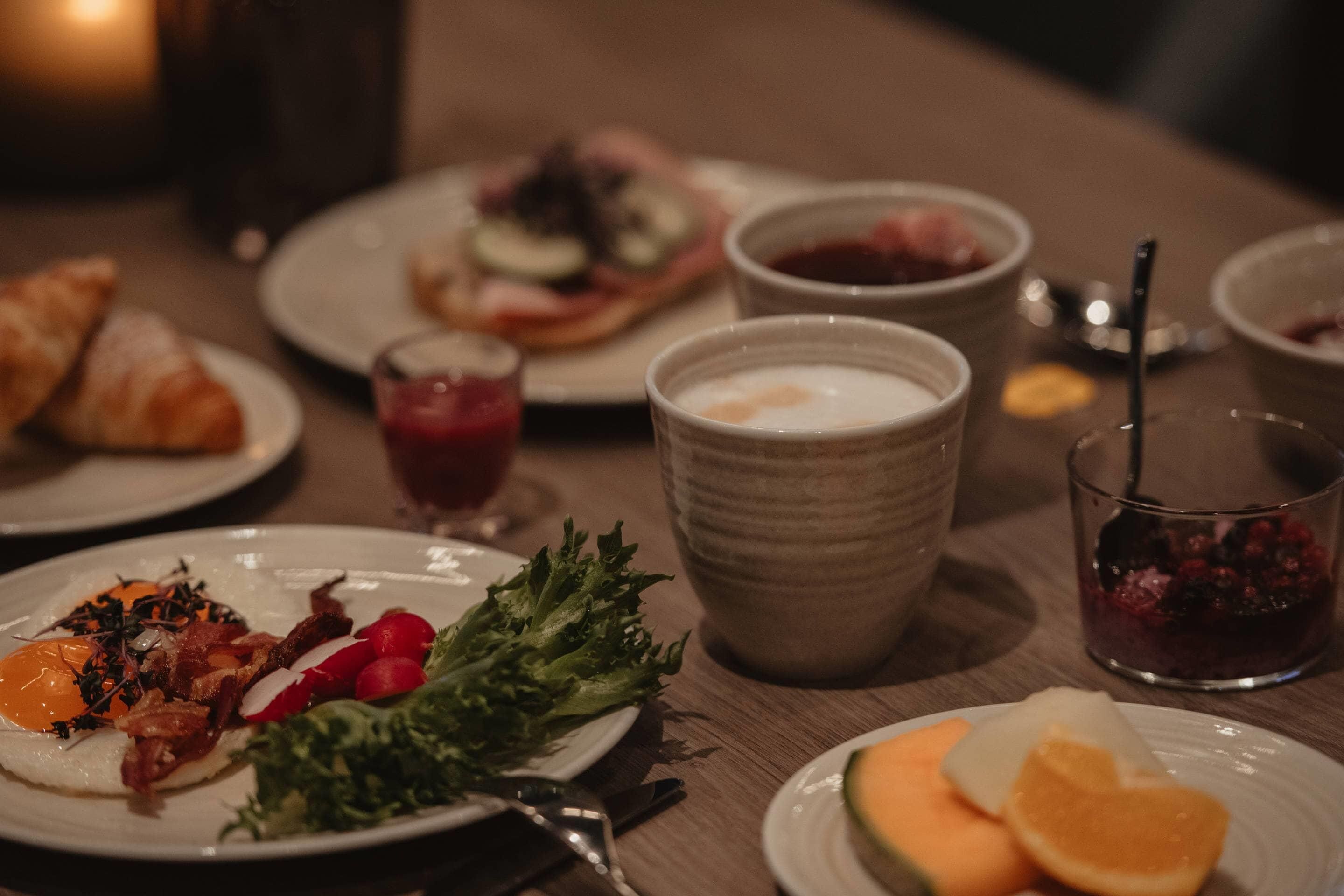 Uma mesa de jantar com pratos de comida, uma tigela de sopa e um copo de suco.