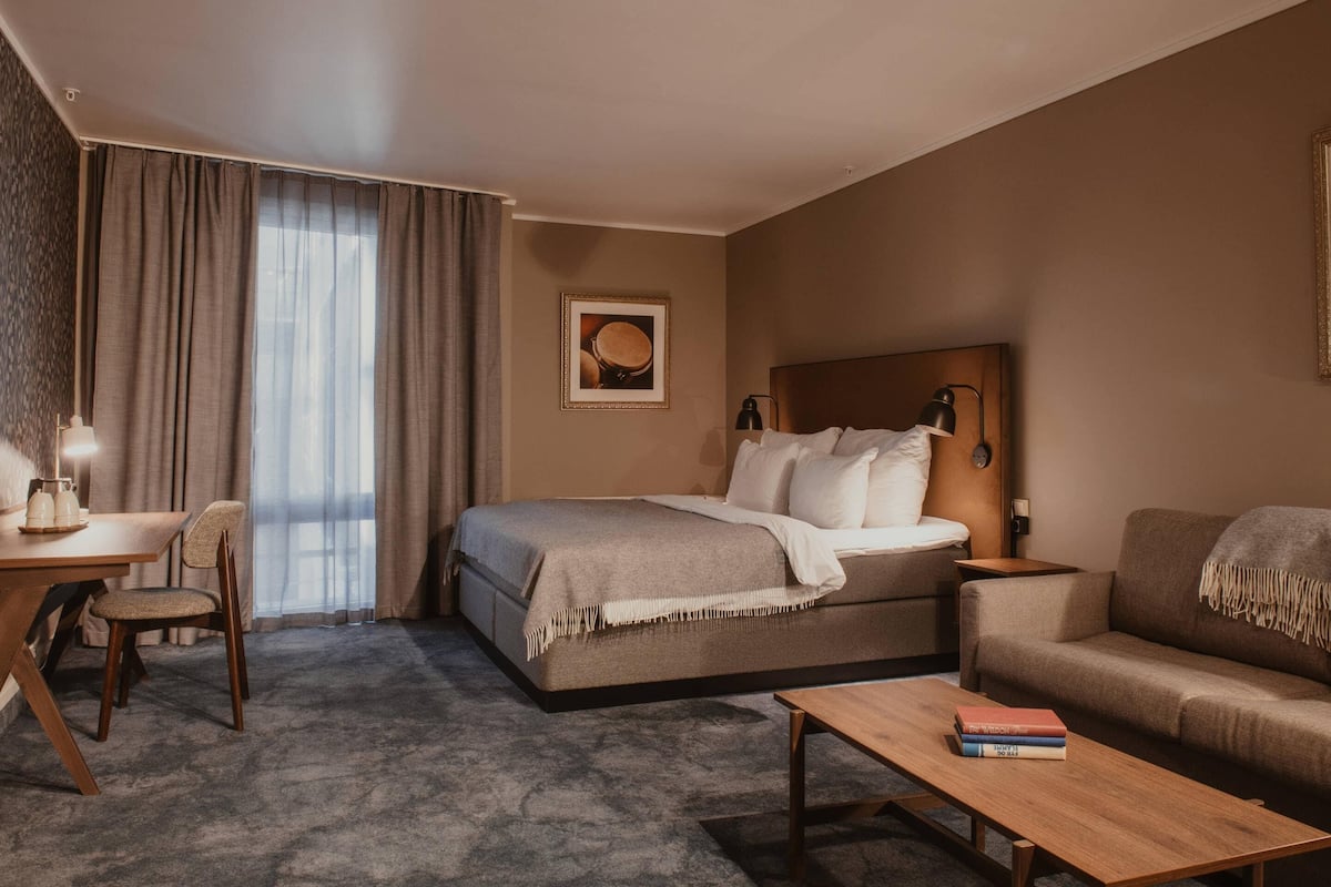 Hotellihuone, jossa on sänky, sohva, työpöytä ja tuoli.