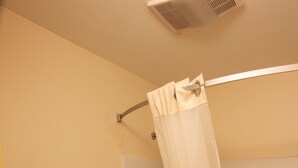 A bathroom with a toilet, a bathtub, and a shower curtain. - Texas Inn & Suites (Pharr)