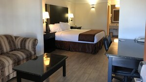 A hotel room with a bed, a desk, a chair, a sofa, and a bathroom visible in the background. - Texas Inn & Suites (Pharr)