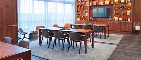 A modern conference room with a large table, chairs, and a television.