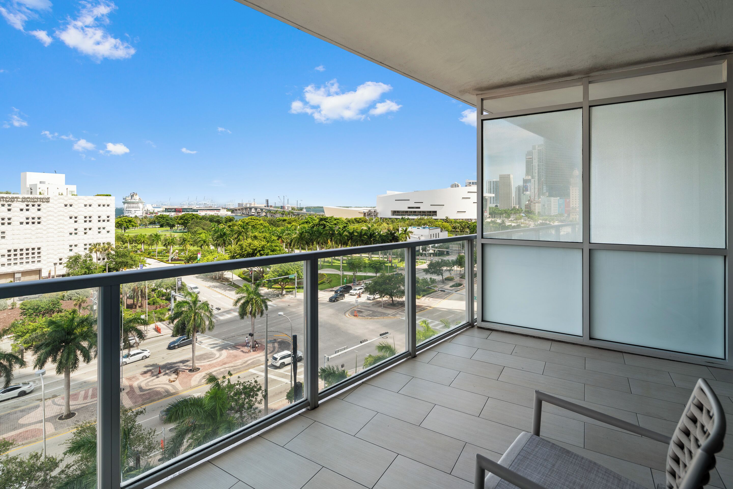 A balcony with a city view, a chair, and a table.