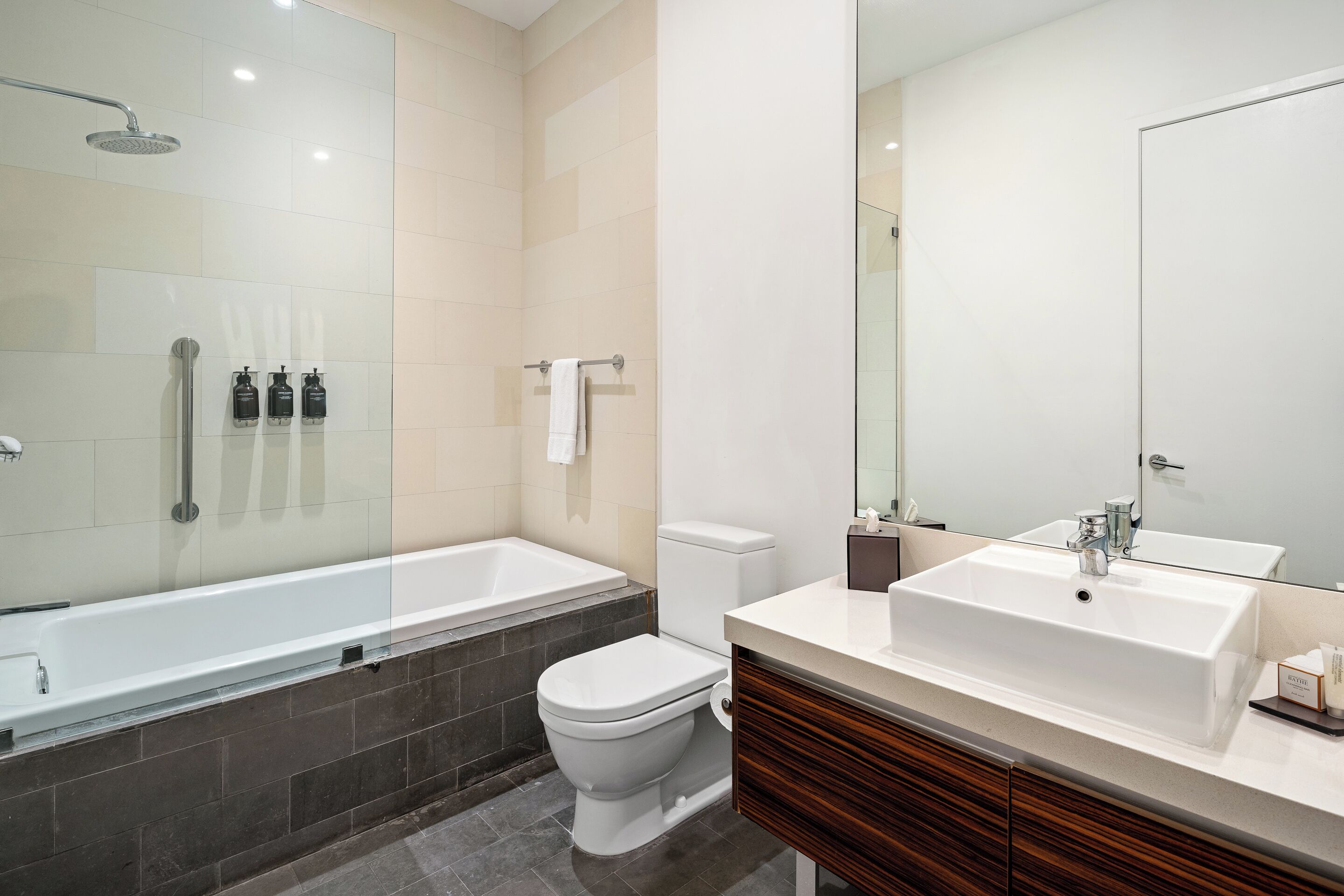 A modern bathroom with a bathtub, toilet, and vanity with a sink.