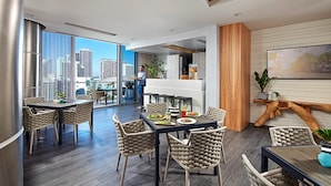 A modern dining area with a view of the city skyline, featuring a large dining table with chairs, a piano, and a wooden accent wall. - The Grayson Miami Downtown (Miami)