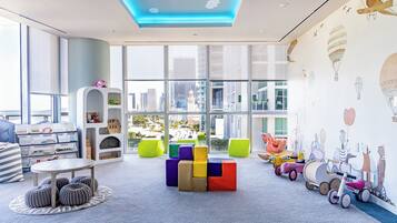 Un moderno cuarto de juegos infantiles con bloques de colores, una mesa de juegos y vistas a la ciudad.