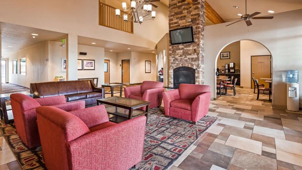 A spacious lobby with a fireplace, red upholstered chairs, a brown leather sofa, and a dining area. - Best Western Rambler (Walsenburg)